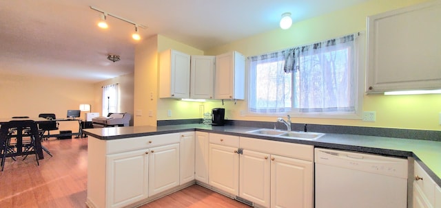 kitchen with a sink, dark countertops, dishwasher, and light wood-style flooring