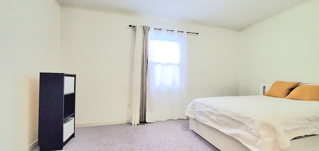 bedroom with crown molding, light colored carpet, and baseboards