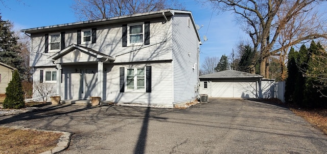 colonial-style house with entry steps, an outdoor structure, central AC unit, and a garage