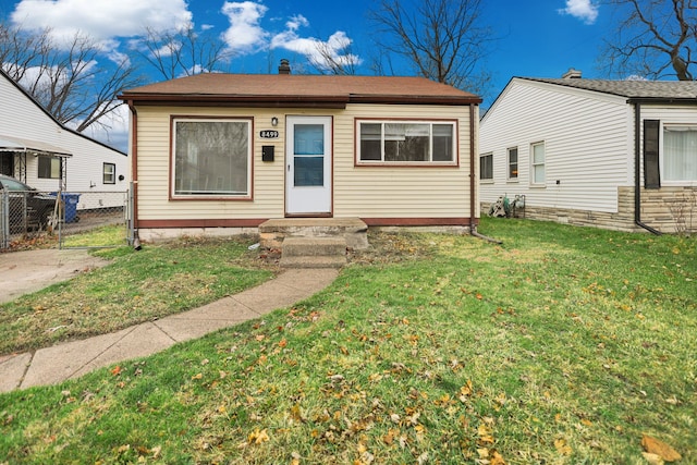 bungalow-style house featuring a gate, fence, and a front lawn