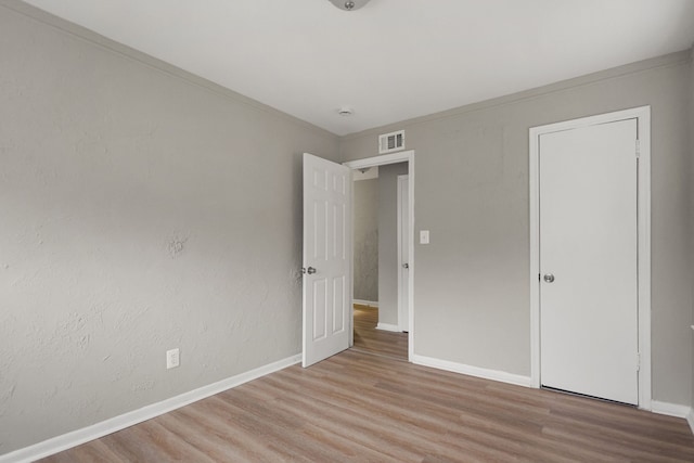 unfurnished bedroom with light wood-style flooring, visible vents, and baseboards