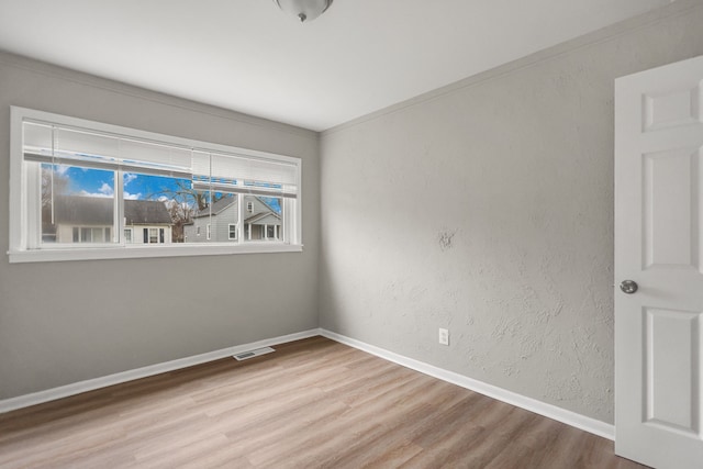 unfurnished room with visible vents, a textured wall, baseboards, and wood finished floors