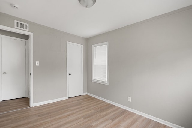 unfurnished bedroom with a closet, baseboards, visible vents, and light wood finished floors