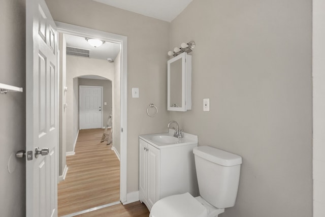 bathroom featuring visible vents, toilet, vanity, wood finished floors, and baseboards