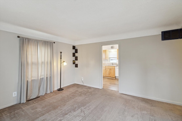 unfurnished room featuring visible vents, light carpet, and baseboards