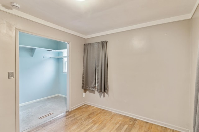 spare room featuring light wood finished floors, visible vents, and baseboards