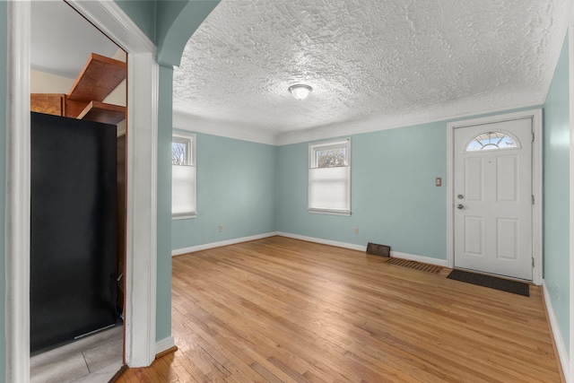 entrance foyer featuring a textured ceiling, light wood-style flooring, and baseboards