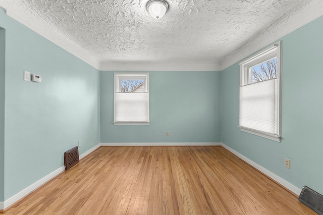 unfurnished room featuring a textured ceiling, wood finished floors, visible vents, and baseboards