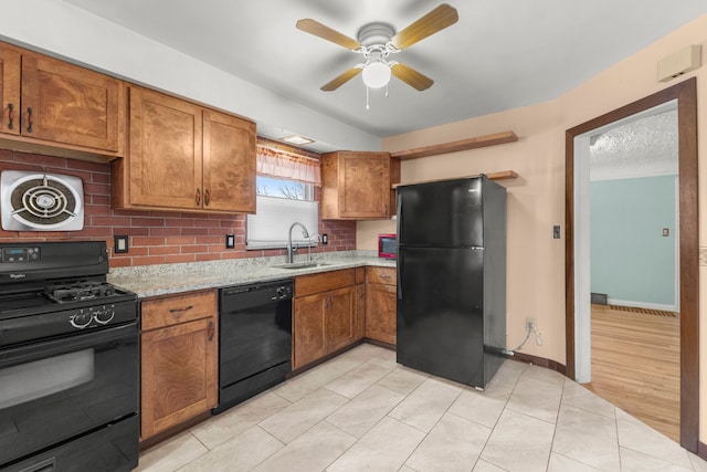 kitchen with tasteful backsplash, visible vents, brown cabinets, black appliances, and a sink