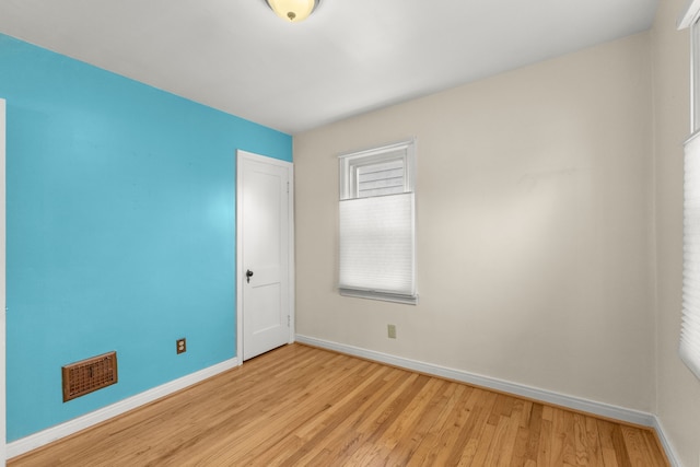 unfurnished room with light wood finished floors, baseboards, and visible vents