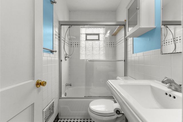 full bathroom with toilet, a sink, tile walls, water heater, and combined bath / shower with glass door