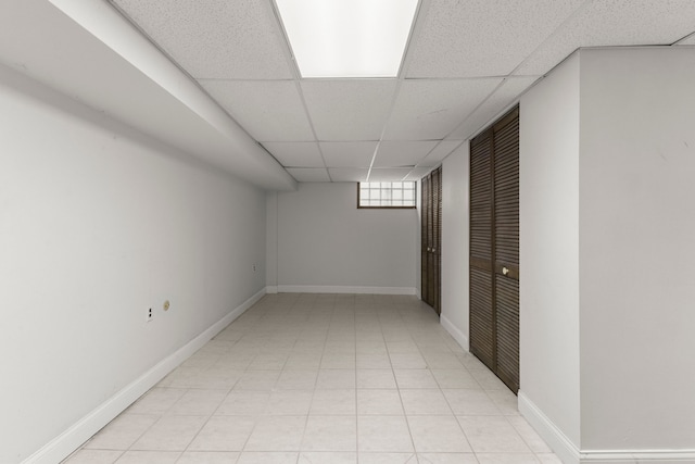 below grade area with a paneled ceiling and baseboards