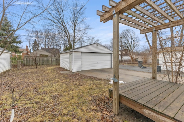 view of yard with a detached garage, fence, a pergola, and an outbuilding