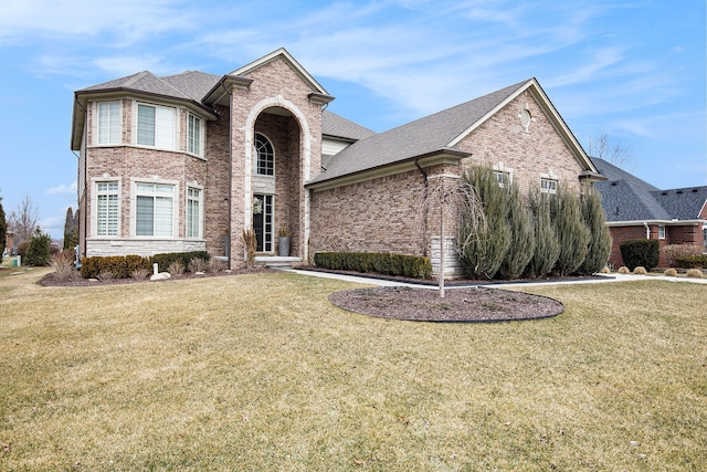 view of front facade with a shingled roof, brick siding, and a front lawn