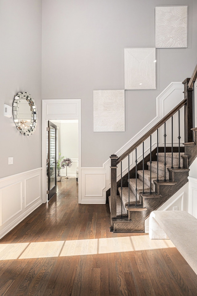 stairs featuring a wainscoted wall, wood finished floors, and a decorative wall