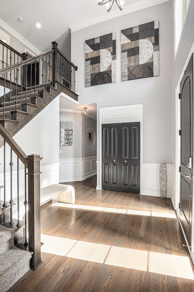 foyer entrance featuring ornamental molding, stairway, a high ceiling, and hardwood / wood-style flooring