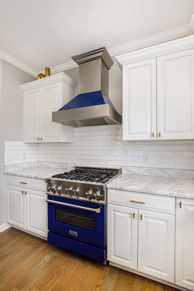 kitchen featuring wall chimney range hood, high end range, and white cabinets