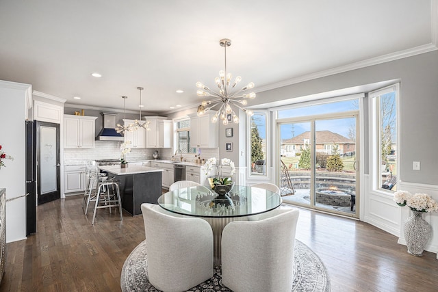 dining area featuring dark wood-style floors, crown molding, and an inviting chandelier