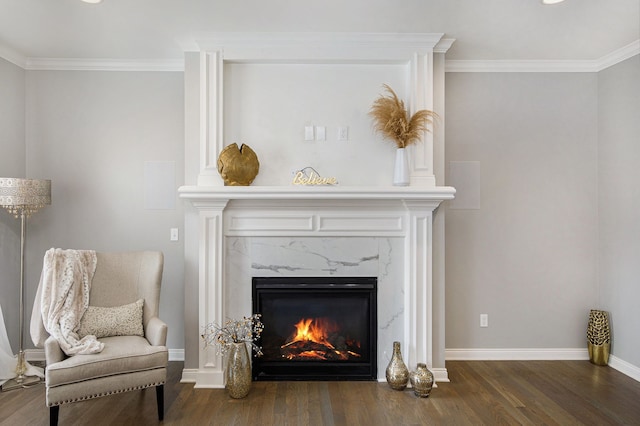 sitting room with crown molding, a premium fireplace, wood finished floors, and baseboards