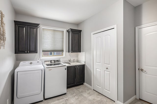 clothes washing area featuring baseboards, a sink, cabinet space, and washer and dryer