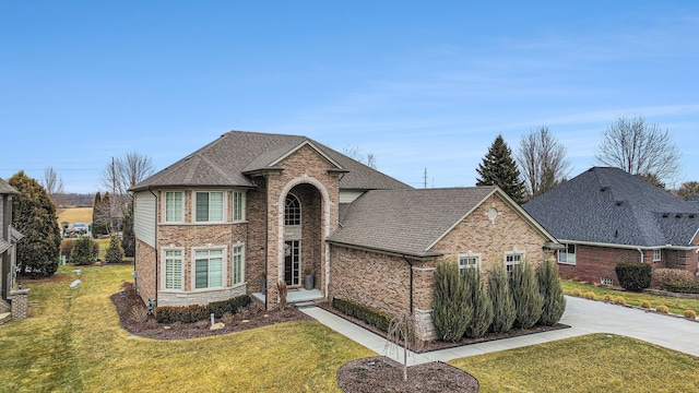 traditional-style home with concrete driveway, brick siding, a front yard, and a shingled roof