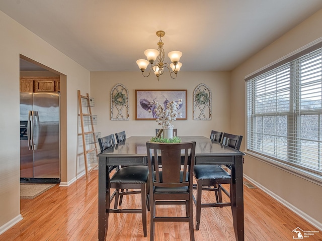 dining area featuring a chandelier, visible vents, light wood-style flooring, and baseboards