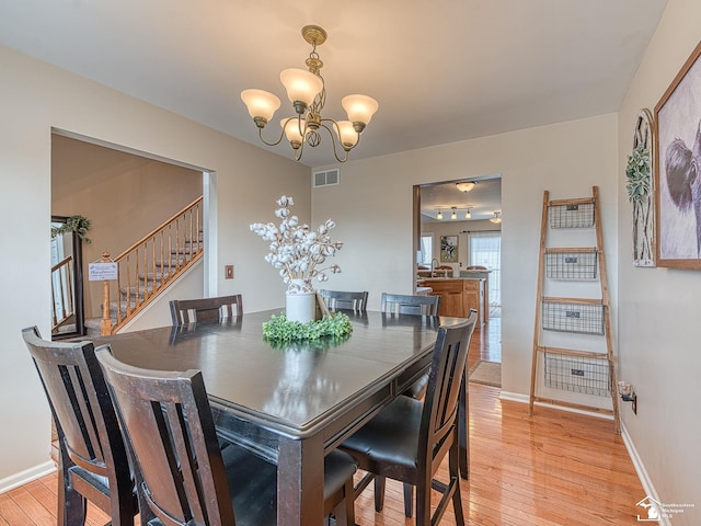 dining space featuring baseboards, visible vents, a notable chandelier, and light wood finished floors