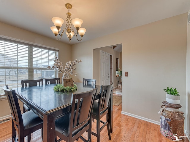 dining area with visible vents, light wood-style flooring, baseboards, and an inviting chandelier