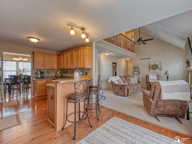 kitchen with a breakfast bar area, a peninsula, visible vents, light wood-style floors, and open floor plan