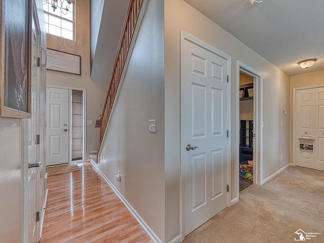 foyer entrance featuring stairs, light carpet, and baseboards