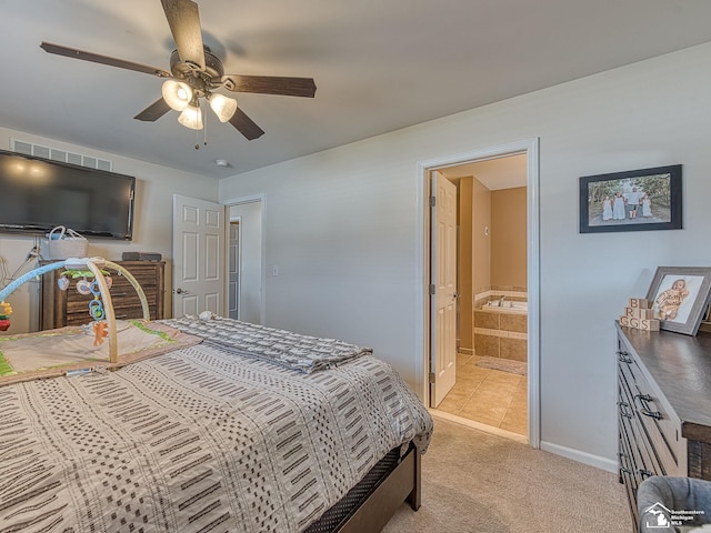 bedroom with light tile patterned flooring, light carpet, a ceiling fan, baseboards, and ensuite bath