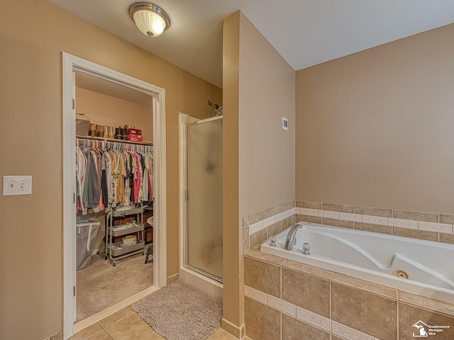 bathroom featuring a spacious closet, a stall shower, a garden tub, and tile patterned floors