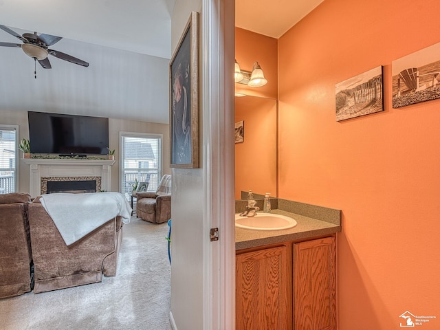 bathroom featuring a ceiling fan, vanity, and a tiled fireplace