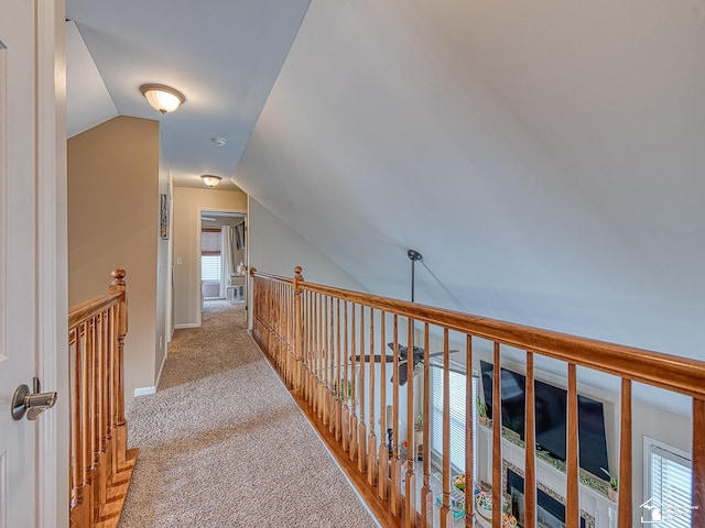 corridor with carpet floors, vaulted ceiling, and an upstairs landing