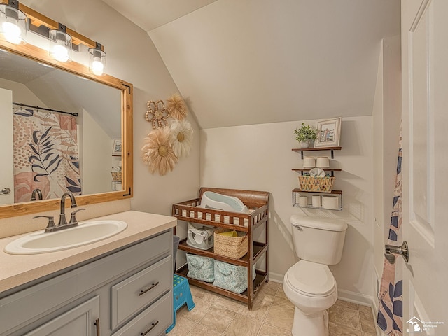 bathroom featuring toilet, baseboards, vaulted ceiling, and vanity