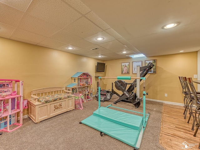 recreation room featuring baseboards, wood finished floors, a drop ceiling, and recessed lighting