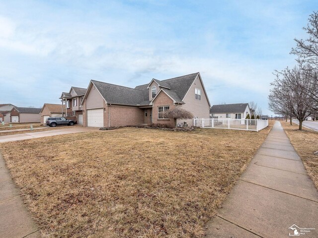 view of front of home featuring an attached garage, brick siding, fence, driveway, and a front yard