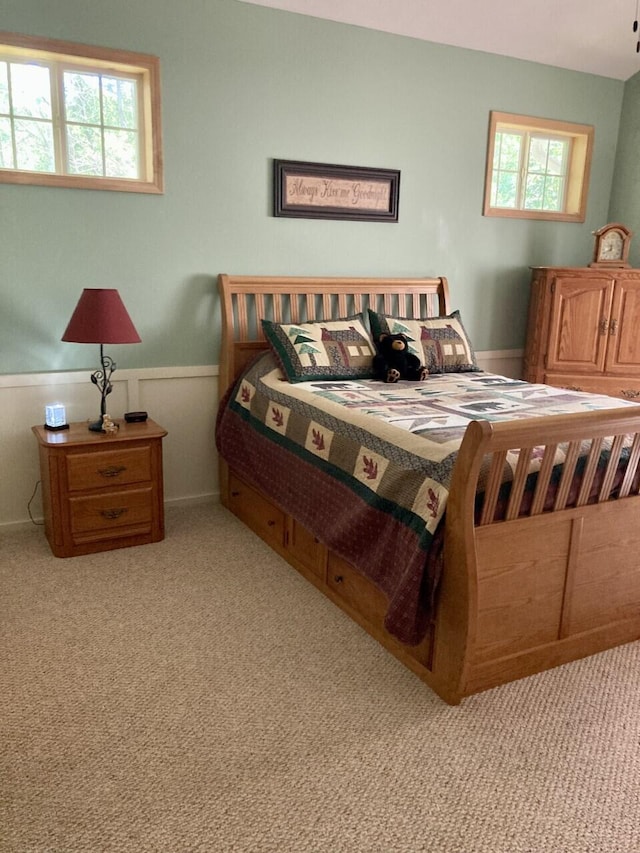 bedroom featuring a wainscoted wall and light colored carpet