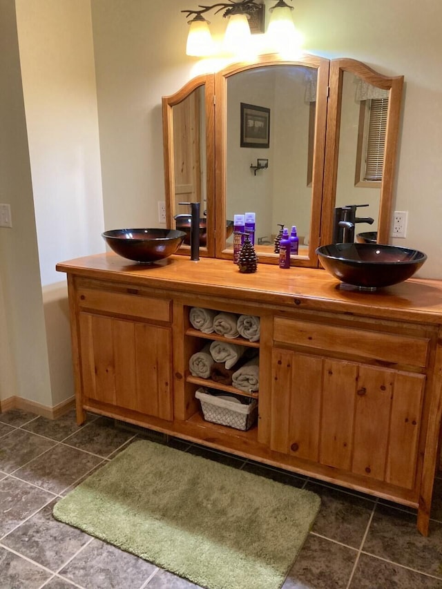 full bathroom featuring double vanity, a sink, and baseboards
