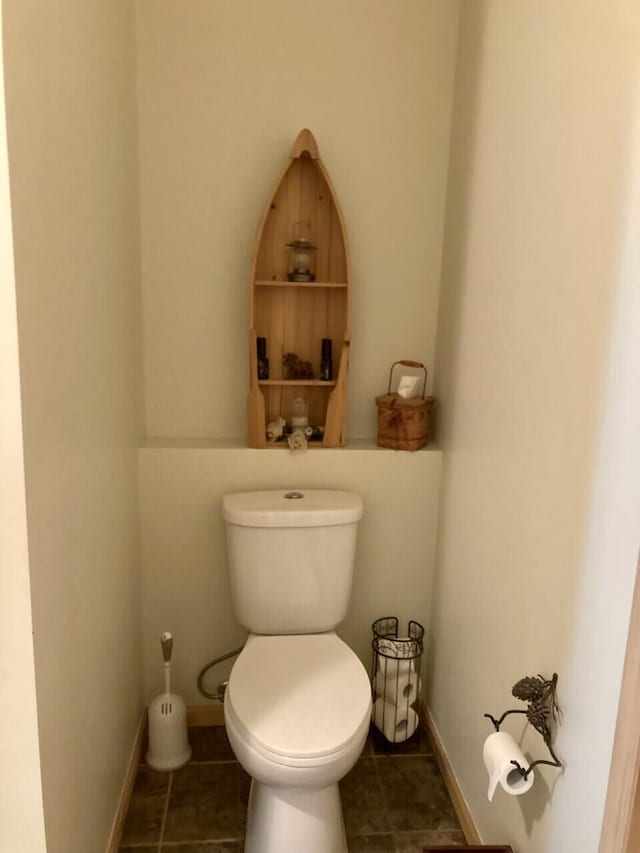 half bathroom featuring tile patterned flooring, toilet, and baseboards