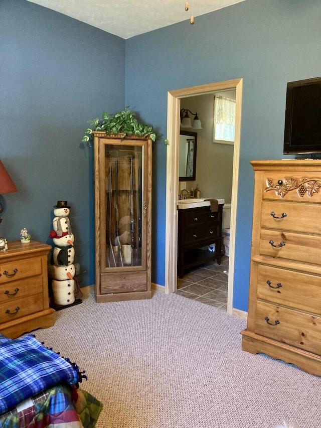 bedroom with ensuite bath, carpet flooring, and baseboards