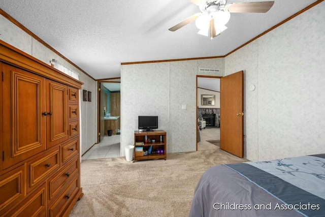 bedroom with light colored carpet, visible vents, ornamental molding, a stone fireplace, and a textured ceiling