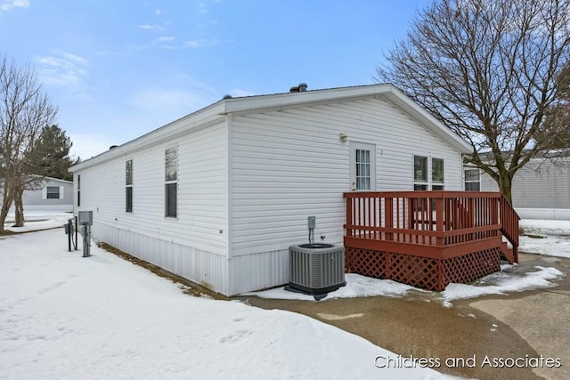 snow covered house featuring central AC and a wooden deck