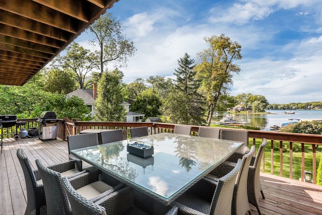 wooden deck with outdoor dining space, area for grilling, and a water view