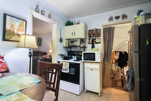 kitchen with white microwave, range with electric cooktop, light wood-style floors, freestanding refrigerator, and stainless steel microwave