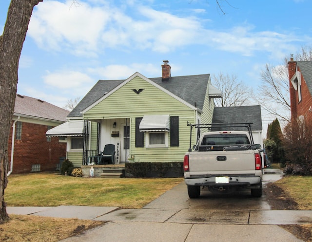 bungalow with a front yard, roof with shingles, and a chimney