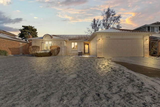 single story home featuring an attached garage, driveway, and brick siding