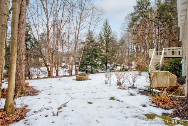 yard layered in snow featuring a fire pit, stairway, and a wooden deck