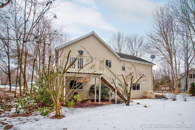 snow covered back of property featuring stairs