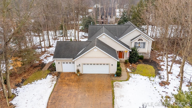 traditional-style home featuring a shingled roof, concrete driveway, and an attached garage